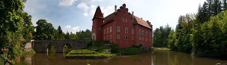 Zámek Červená Lhota s mostem přes řeku v přírodě.