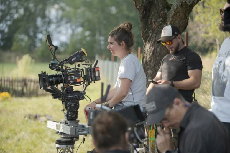 Pozadí natáčení s kamerou a členy filmového týmu venku.