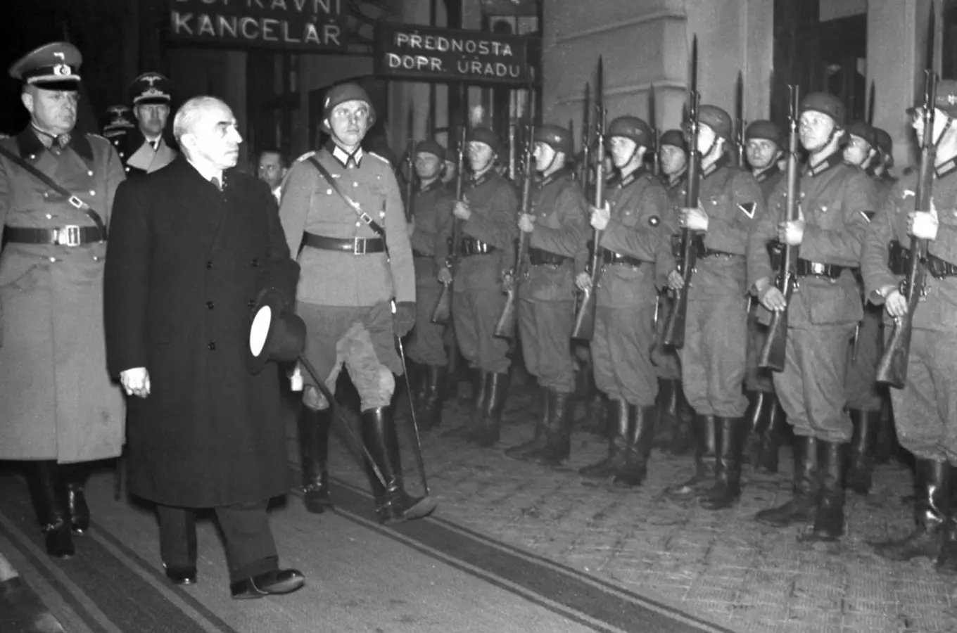 Emil Hácha prochází kolem vojenské stráže v noci.
