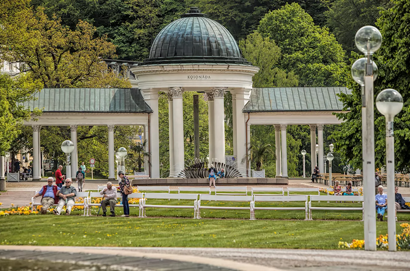Památník Kolonáda v Mariánských Lázních s lidmi na lavičkách.