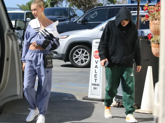 Hailey Bieber chodí v parkovišti s další osobou.
