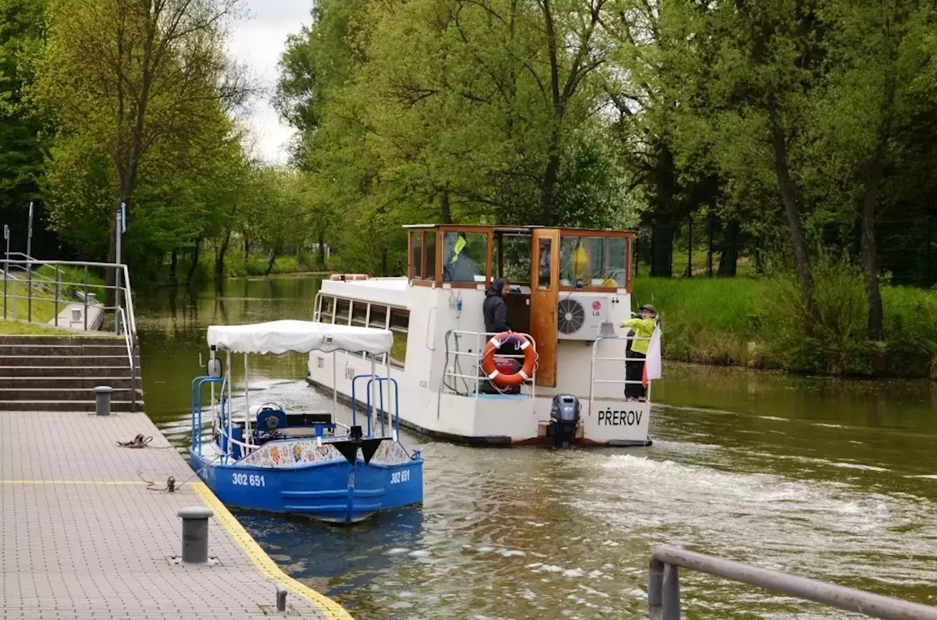 Dvě turistické lodě na řece s okolní zelení