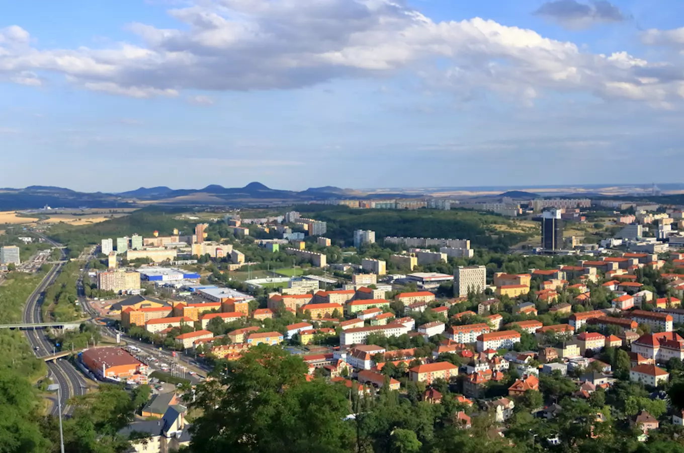 Pohled na město Most s okolními kopci pod oblohou.