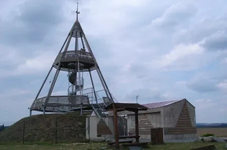 Výhledová rozhledna na kopci s budovami pod šedou oblohou.