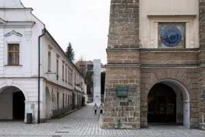 Historická brána Litomyšle s kamennou věží a bílými domy.