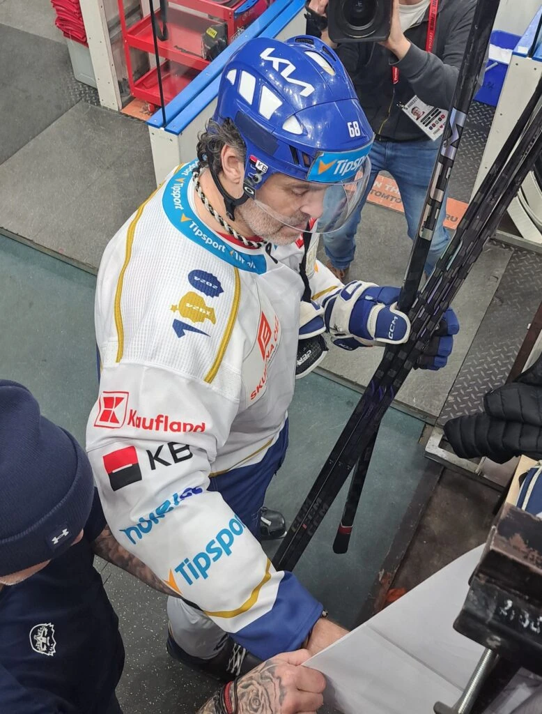 Jaromír Jágr v hokejovém dresu s helmetem drží hokejkou.