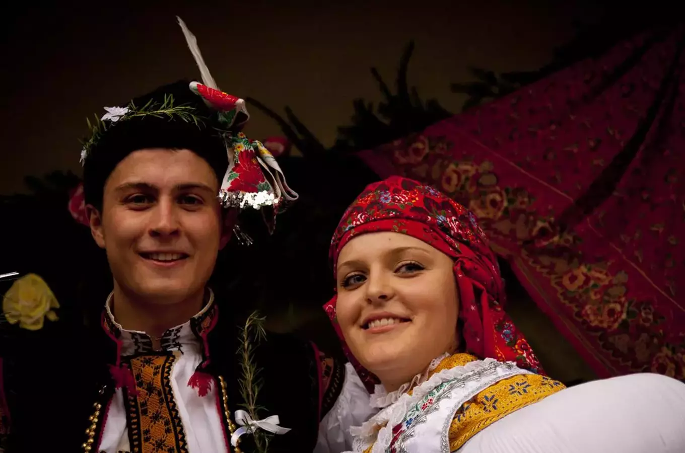 Muž a žena v tradičních krojích se usmívají na fotografii.