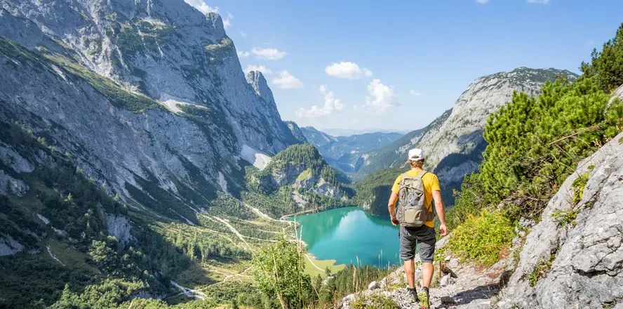 Turista na stezce s výhledem do rakouských Alp k jezeru.