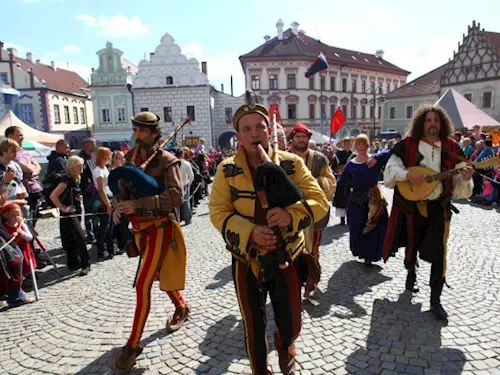 Skupina hudebníků v historických kostýmech hraje na nástroje.