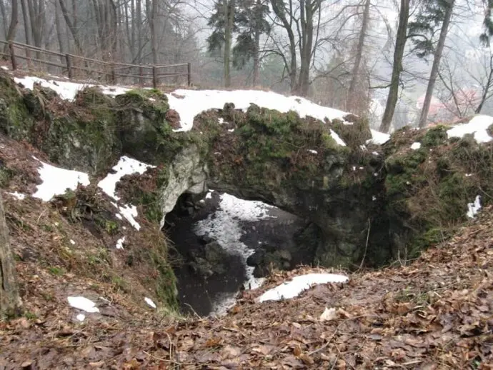 Přirozený skalní oblouk v zimním lese na Moravskoslezsku.