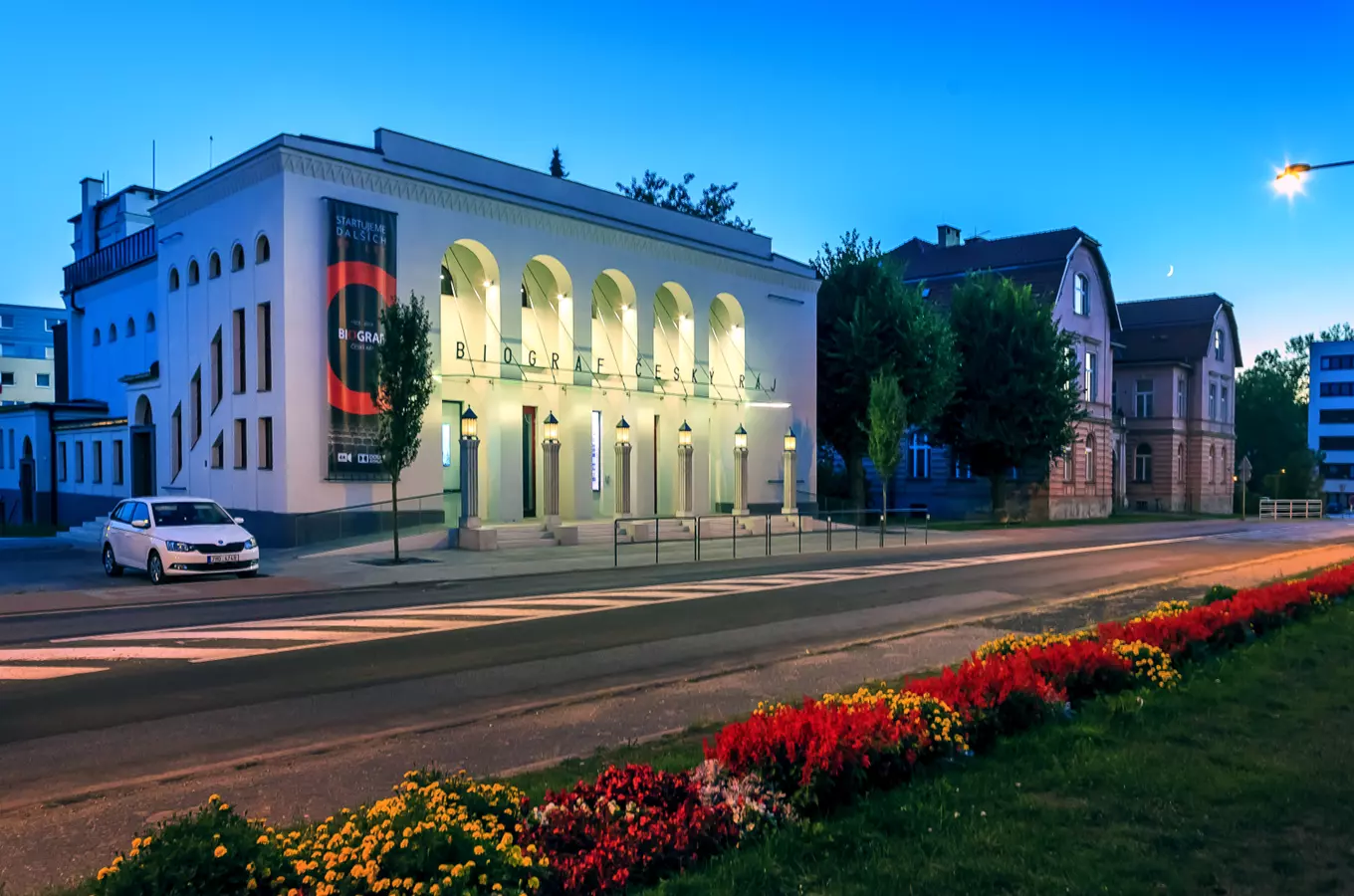 Biograf Český ráj v Čechách s květinami před vstupem.