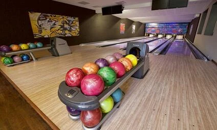 Vnitřek bowlinového centra s barevnými koulemi na dráze.