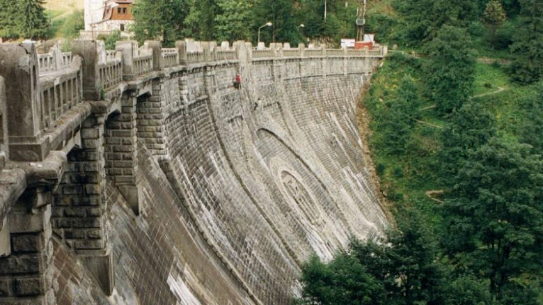 Velká betonová přehrada v zeleném lesním prostředí ve Špindlerově Mlýně.