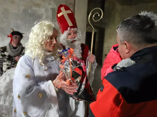 Osoba v kostýmu sv. Mikuláše dává dárek na akci.