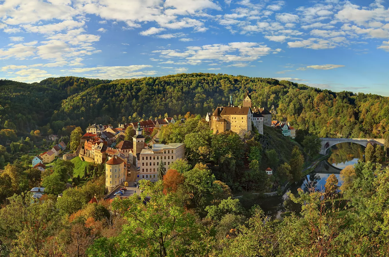 Pohled na hrad Loket s vesnicí podél řeky v krajině.