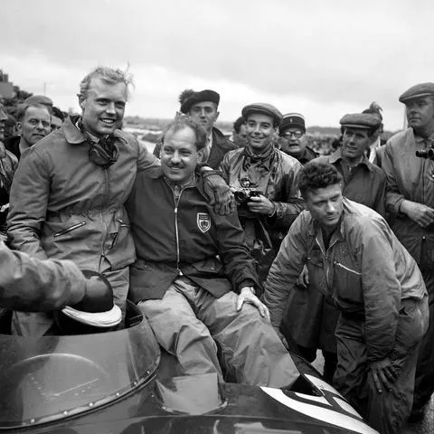 Historická fotografie motoristického závodního týmu s řidičem kolem motocyklu.