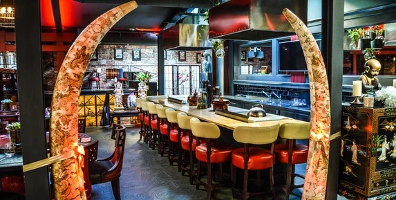 Vnitřek asijské restaurace s dlouhým stolem pro společné jídlo.