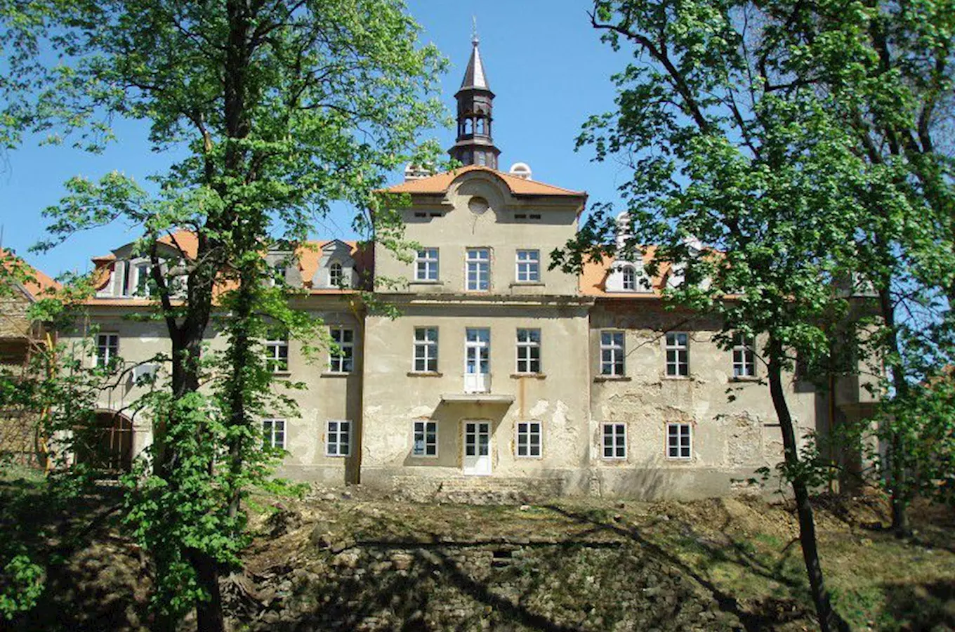 Zámek Svinaře s věží mezi stromy na slunečný den
