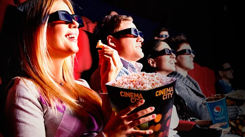 Lidé v kině jedí popcorn při sledování filmu.