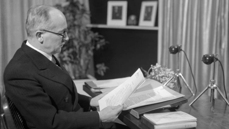 Edvard Beneš sedí u stolu a čte dokumenty v kanceláři.