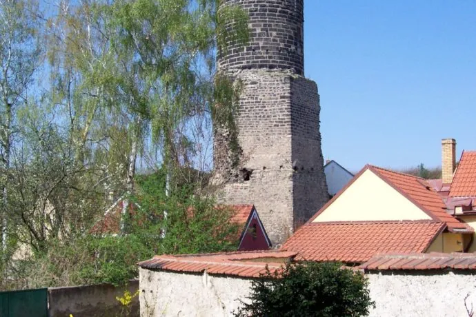 Stará kamenná věž s červenými střechami v kraji.