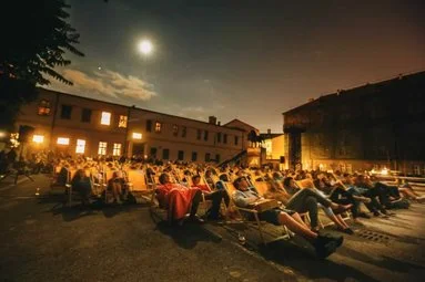 Večerní venkovní promítání s diváky na pražském náměstí.