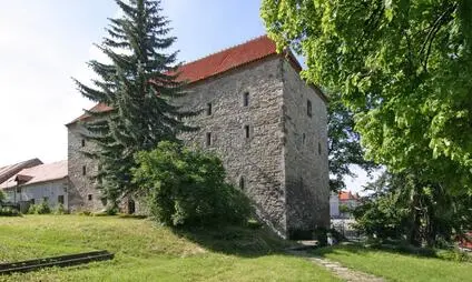 Historická kamenná věž v okolí Volyňe s červenou střechou.
