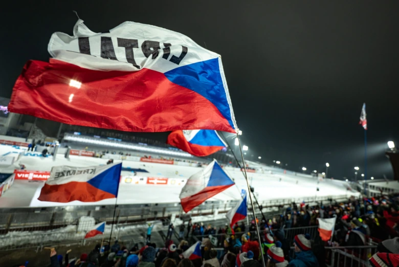 Fotografie diváků s českými vlajkami na nočním sportovním utkání.