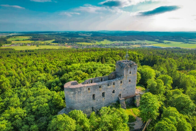 Ruina hradu v lesích s výhledem na krajinu.