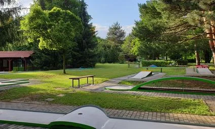 Minigolfový hřiště s trávníkem, rampami a stromy v Plzni