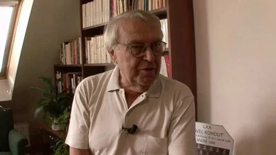 Starosta Pavel Kohout sedí v knihovně s knihami za zády.