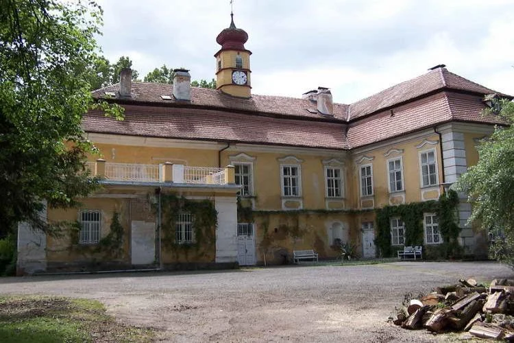 Historický žlutý zámek s věží v Křimicích.