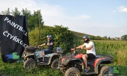 Dva lidé jezdí na čtverokolech venku v přírodě.