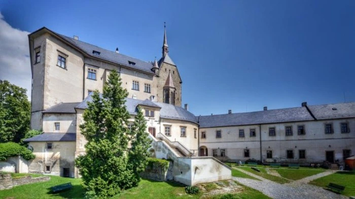 Dvůr hradu v Hlinsku s věží a zelenou zahradou.