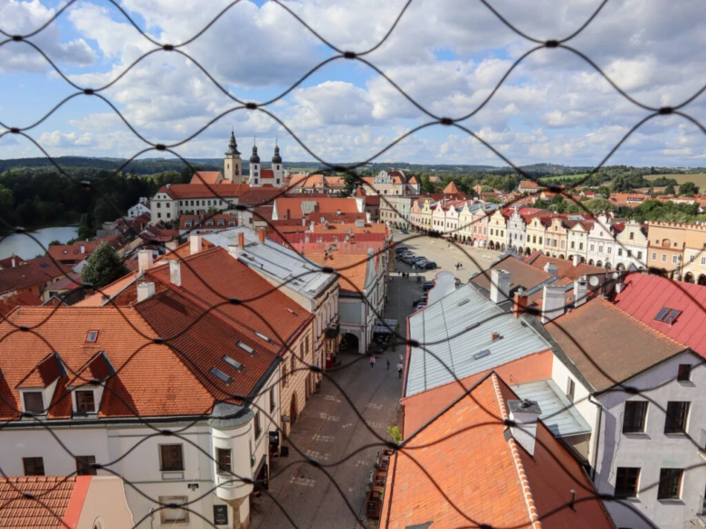 Pohled na náměstí v Telči skrz ochrannou mříž.