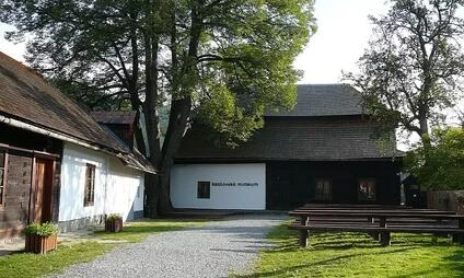 Muzeum v Velkých Károlovicích s dřevěnou budovou a zahradou.