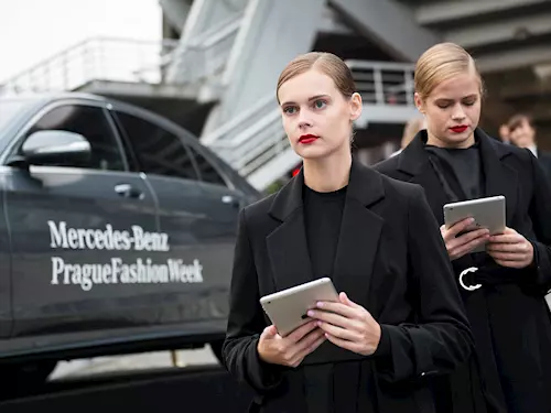 Dvě modelky na Pražském týdnu módy u auta s logem.