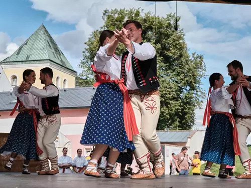 Tanečníci v tradičních kostýmech vystupují na venkovním pódiu.