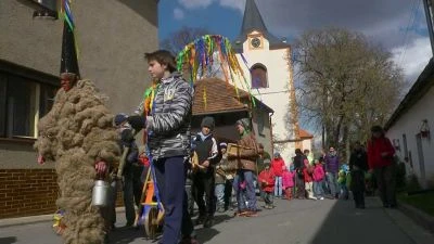 Lidé s velikonocní figurou ze slámy na ulici vesnice.