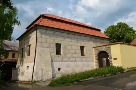Historická kamenná budova s červenou střechou v Nymburku.