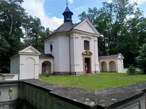 Bílá kaple na Černé hoře v lesu s arkádami.