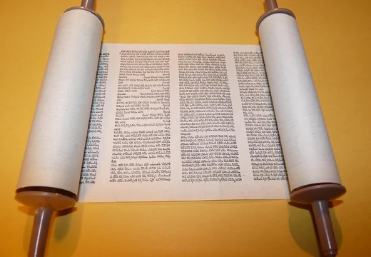 Otevřený svitek s hebrejským textem na žlutém pozadí.